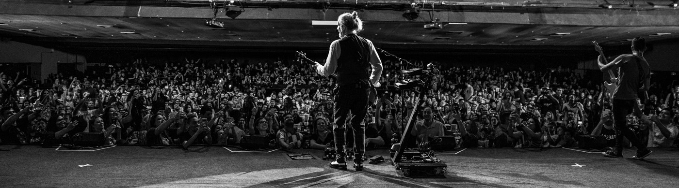 Banner Humberto Gessinger em cima do palco com vista para a plateia em preto e branco